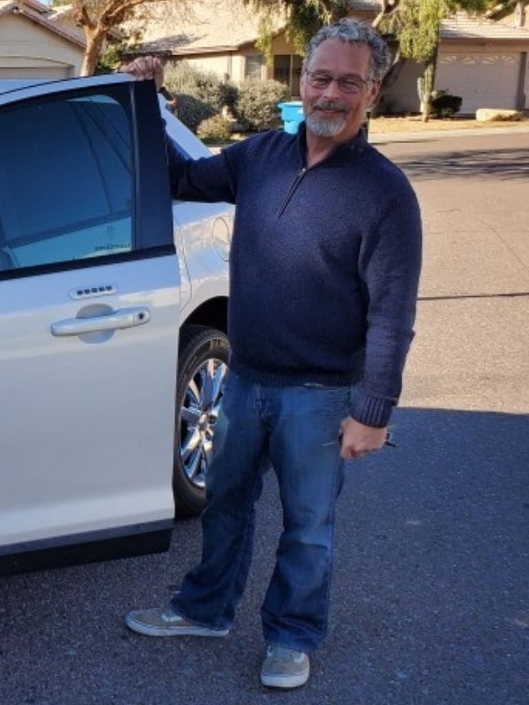 A man standing next to his car on the street.